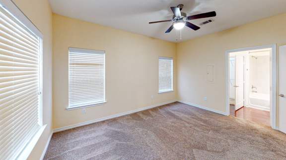 A room with a ceiling fan and carpeted floor.