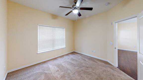 A room with a ceiling fan and carpeted floor.