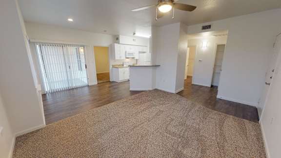 A spacious living room with a carpeted floor and a ceiling fan.