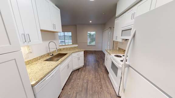 A kitchen with white cabinets and a wooden floor.