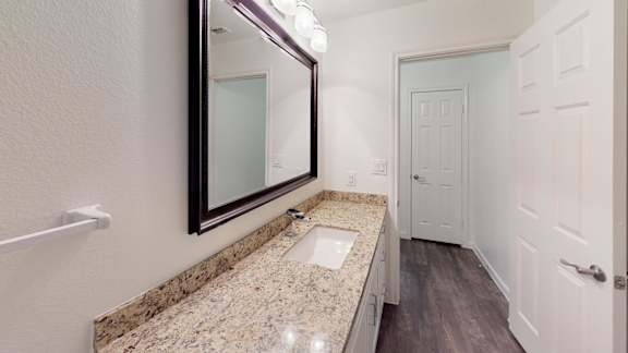 A bathroom with a granite countertop and a large mirror.