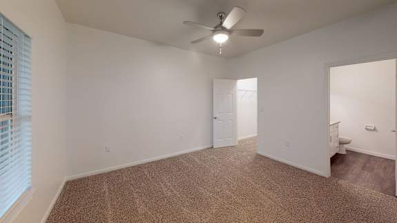 A room with a ceiling fan and carpeted floor.