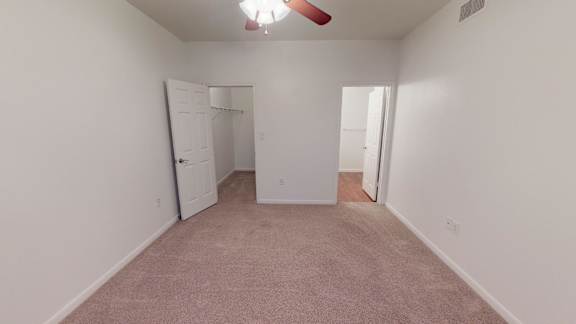A room with a carpeted floor and a ceiling fan.
