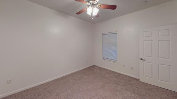 A room with a ceiling fan and a door.