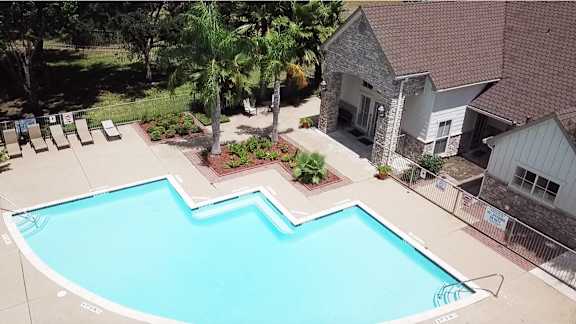 A swimming pool surrounded by a concrete patio and a house.