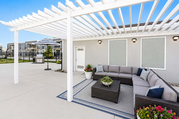 Covered outdoor patio with sectional sofa and coffee table at Park Station Apartments, Midvale, Utah