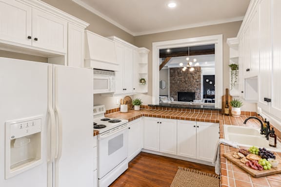 A kitchen with white appliances and wooden floors.