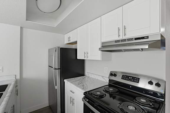 A kitchen with a black stove top oven and white cabinets. at Park Station Apartments, Apartments, Midvale, UT