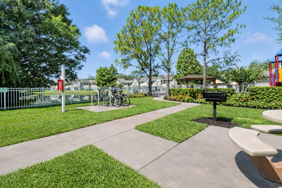 A park with a bench, a fence, and a tree. at Waterbridge Apartments , Apartments, Orlando, FL