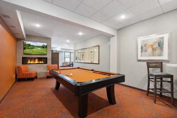 A room with a pool table and a television showing a golf course.