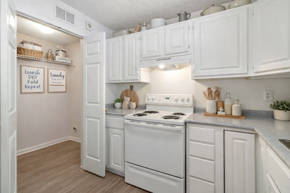 A clean, white kitchen with a sign that says "Laundry Dry Fold Repeat.".