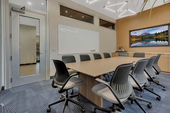 Conference room with whiteboard and wooden table at Prosper West Apartments, Minnesota