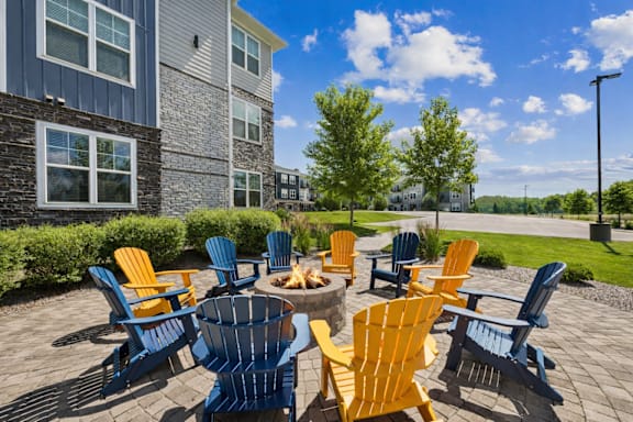 A patio with blue and yellow chairs and a fire pit.