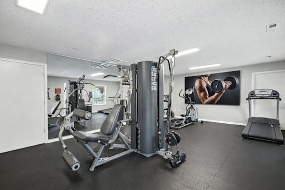 A gym with a variety of equipment including a weight machine, a bench press, and a treadmill.