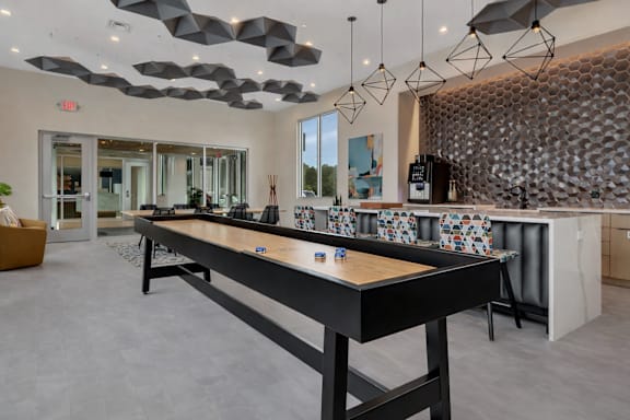 Clubhouse game room with shuffleboard and bar seating at Prosper West Apartments, Waite Park