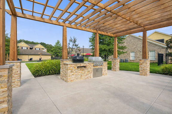 A wooden pergola with stone pillars and a concrete floor.