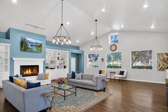 A living room with a grey couch, a fireplace, and a painting on the wall.