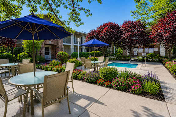 A patio with a table and chairs and umbrellas.