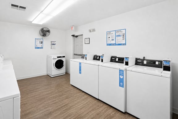 A laundry room with a washer and dryer on the wall and a fan on the ceiling.