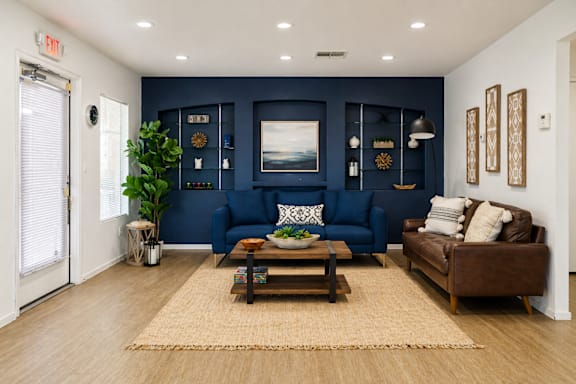 A living room with a blue couch and a brown couch.