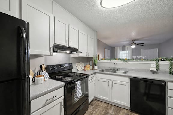 A black stove top oven sits in a kitchen with white cabinets.