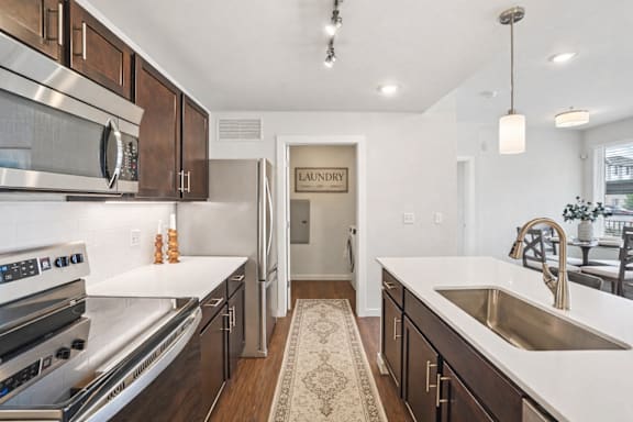 Galley kitchen with stainless appliances and island sink at Connect at First Creek Apartments, Denver, CO