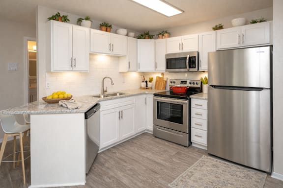 A modern kitchen with white cabinets and stainless steel appliances.