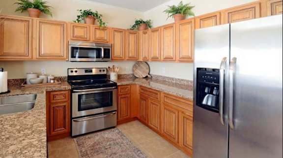 A modern kitchen with a black refrigerator and a large abstract painting on the wall.