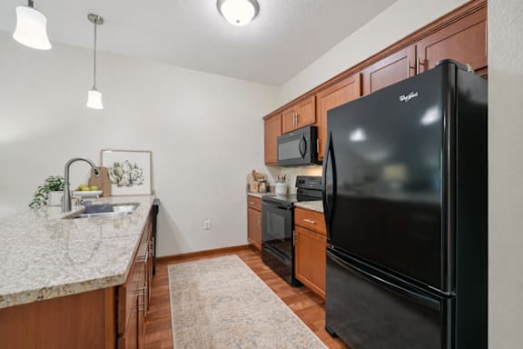 A kitchen with a black fridge and wooden cabinets.