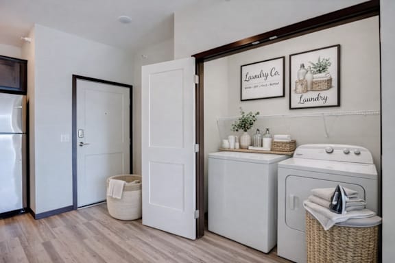 A laundry room with a washer and dryer and a basket of towels.