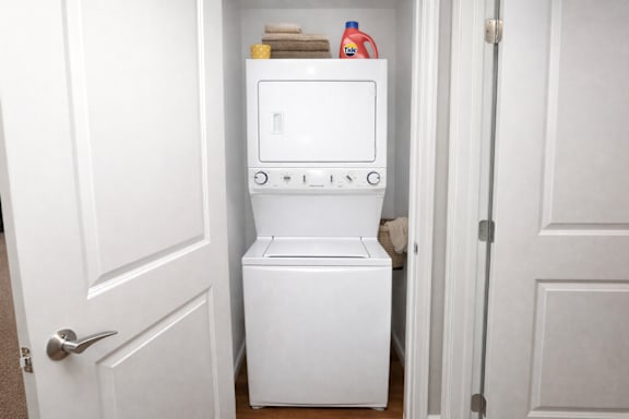 A white washing machine is in a small space between two doors.