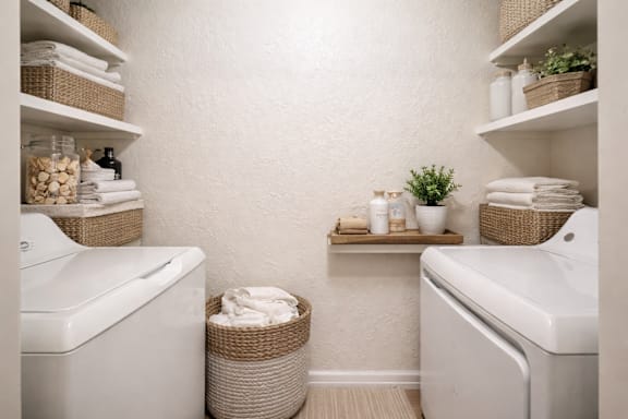 A bathroom with white fixtures and shelves with towels and plants.