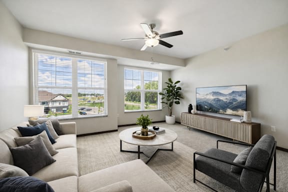A living room with a large couch, a coffee table, and a flat-screen TV.