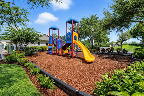 A playground with a yellow slide and a blue and red structure. at Waterbridge Apartments , Florida