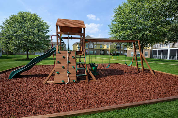 A playground with a green slide and a brown wooden structure.