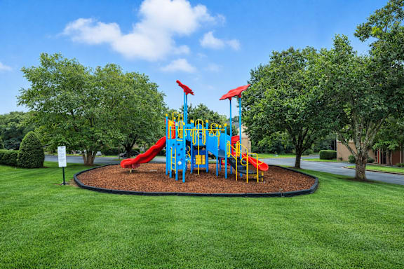 A playground with a blue and yellow structure and a red slide.