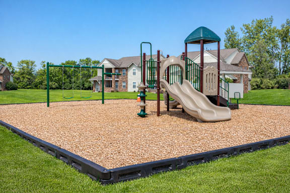 A playground with a slide, swings, and a green tower. at Arbors at Hickory Creek Apartments , University Park, 60484
