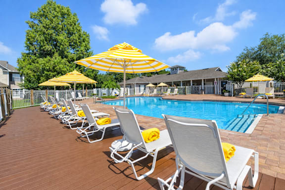 A poolside area with sun loungers and umbrellas. at Waterbridge Apartments , Apartments, Orlando, FL
