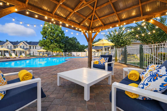 A patio with a table and chairs under a roof with lights. at Waterbridge Apartments , Orlando