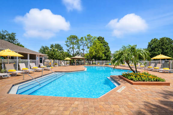 A large outdoor swimming pool surrounded by a brick patio and lounge chairs. at Waterbridge Apartments , Orlando, FL, 32837