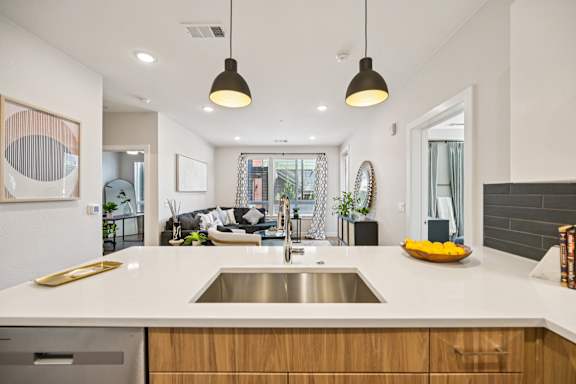 A modern kitchen with a white countertop and wooden cabinets.