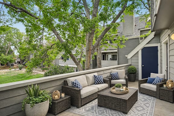 A patio with a couch, table, and potted plants.