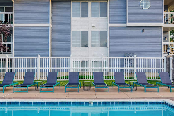 Pool deck with lounge chairs and white railing at Creekview Apartments, Midvale, UT