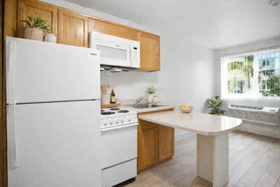 A white refrigerator is in a kitchen with wooden cabinets and a white countertop.