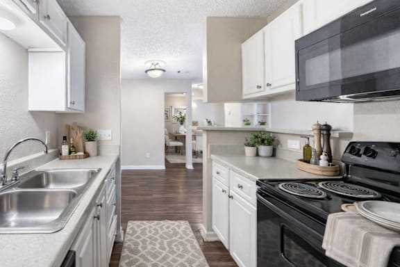 A kitchen with a black microwave, white cabinets, and a black stove. at Parkland at Orange Park Apartments , Orange Park