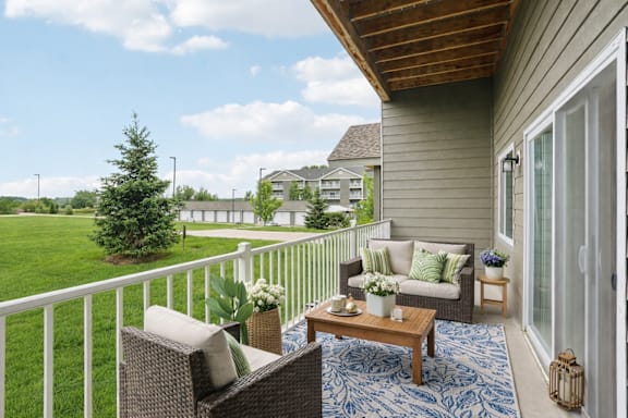 A patio with a white railing, a brown couch, and a blue rug.