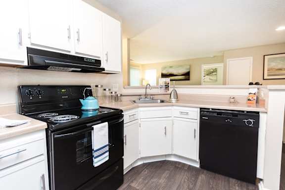 Modern kitchen with black appliances and white cabinets at Delta Crossing Apartments, Charlotte, NC 28212