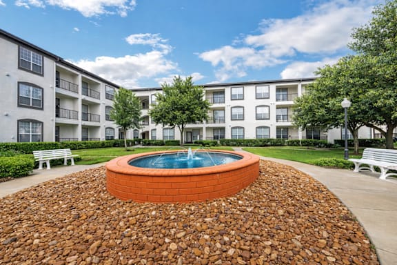 A small fountain in the middle of a courtyard surrounded by a gravel bed.