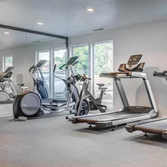 Fitness center with cardio machines and windows at Creekview Apartments, Midvale, 84047
