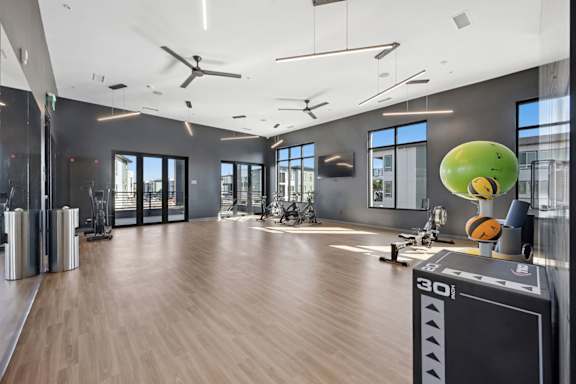 Fitness center with cardio equipment and natural light at Sequel Homes Apartments, Colorado, 80110